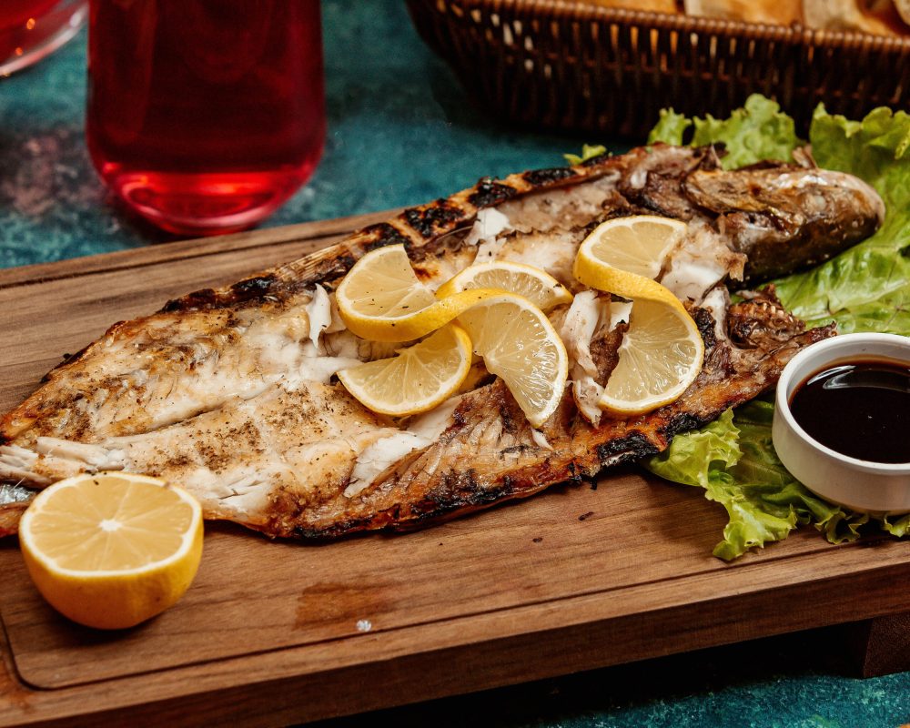fried fish with lemon slices on a wooden board