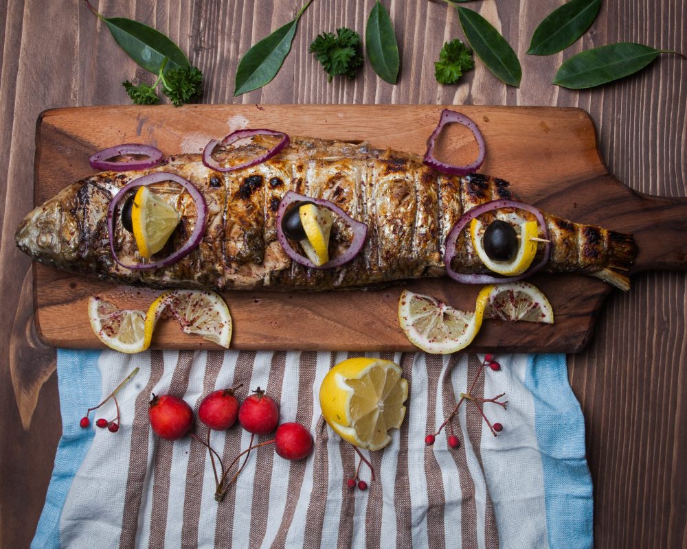 Top view fried fish with lemon and paradise apples and napkins in cutting board on wooden background